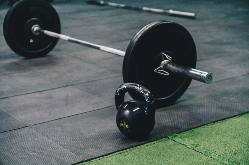 pexels photo 6628962 1 Barbell and kettlebell on gym floor, ideal for fitness and strength training themes.